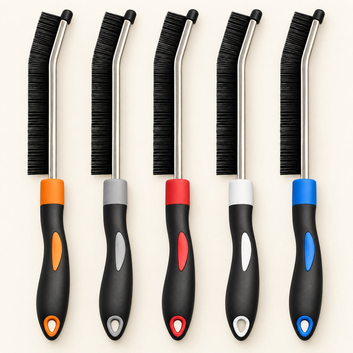 Five slim black crevice cleaning brushes with color-coded handles on a warm ivory background