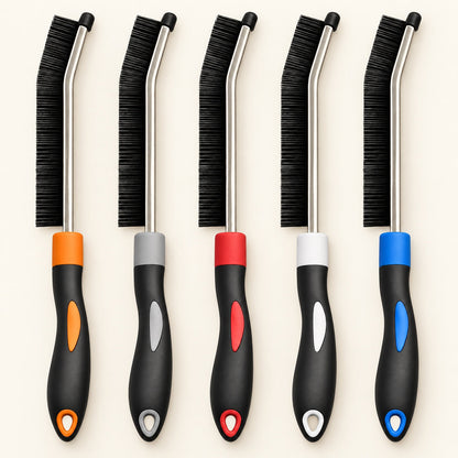Five slim black crevice cleaning brushes with color-coded handles on a warm ivory background